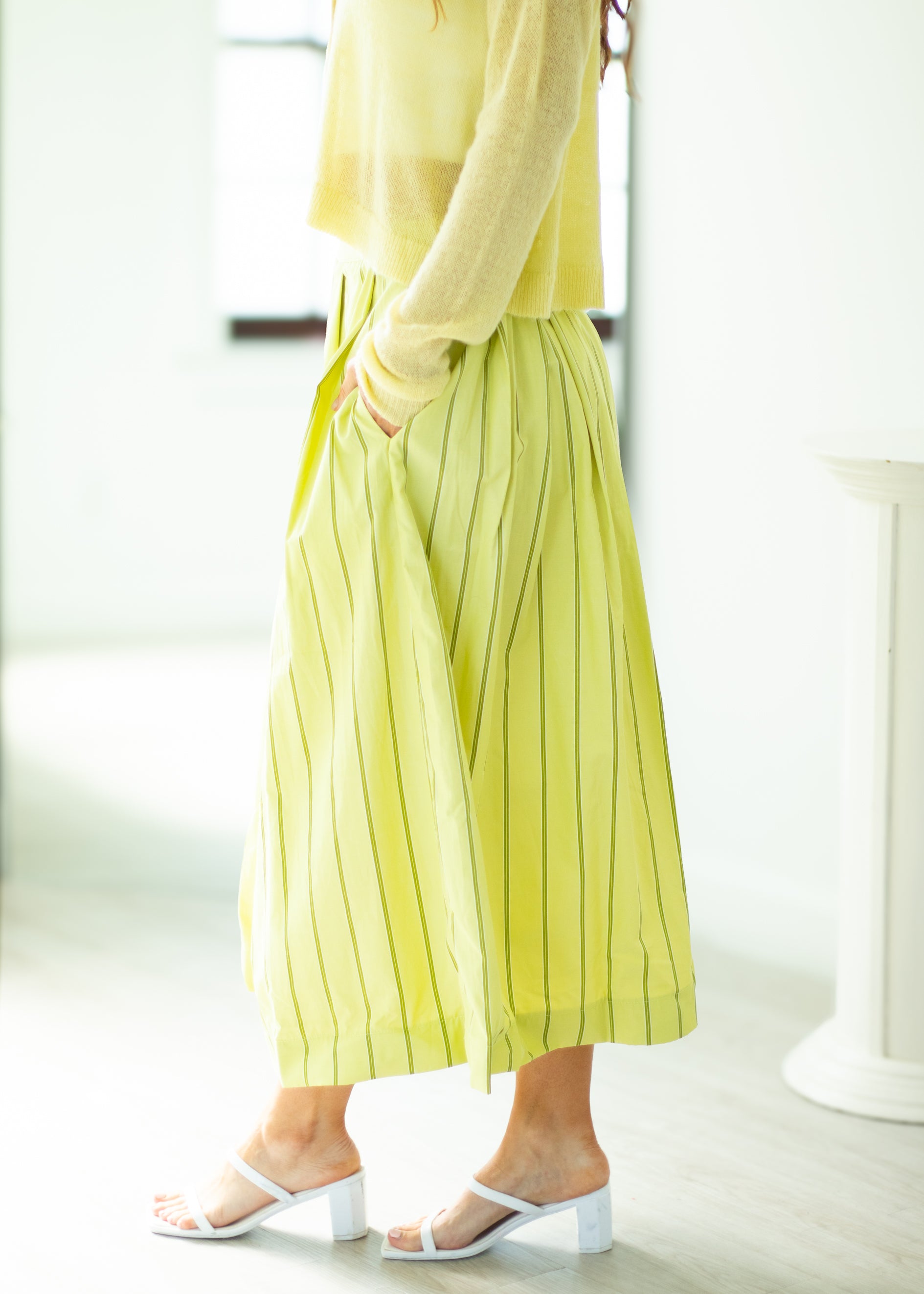 Person wearing a yellow outfit with wide-leg pants in a bright indoor setting
