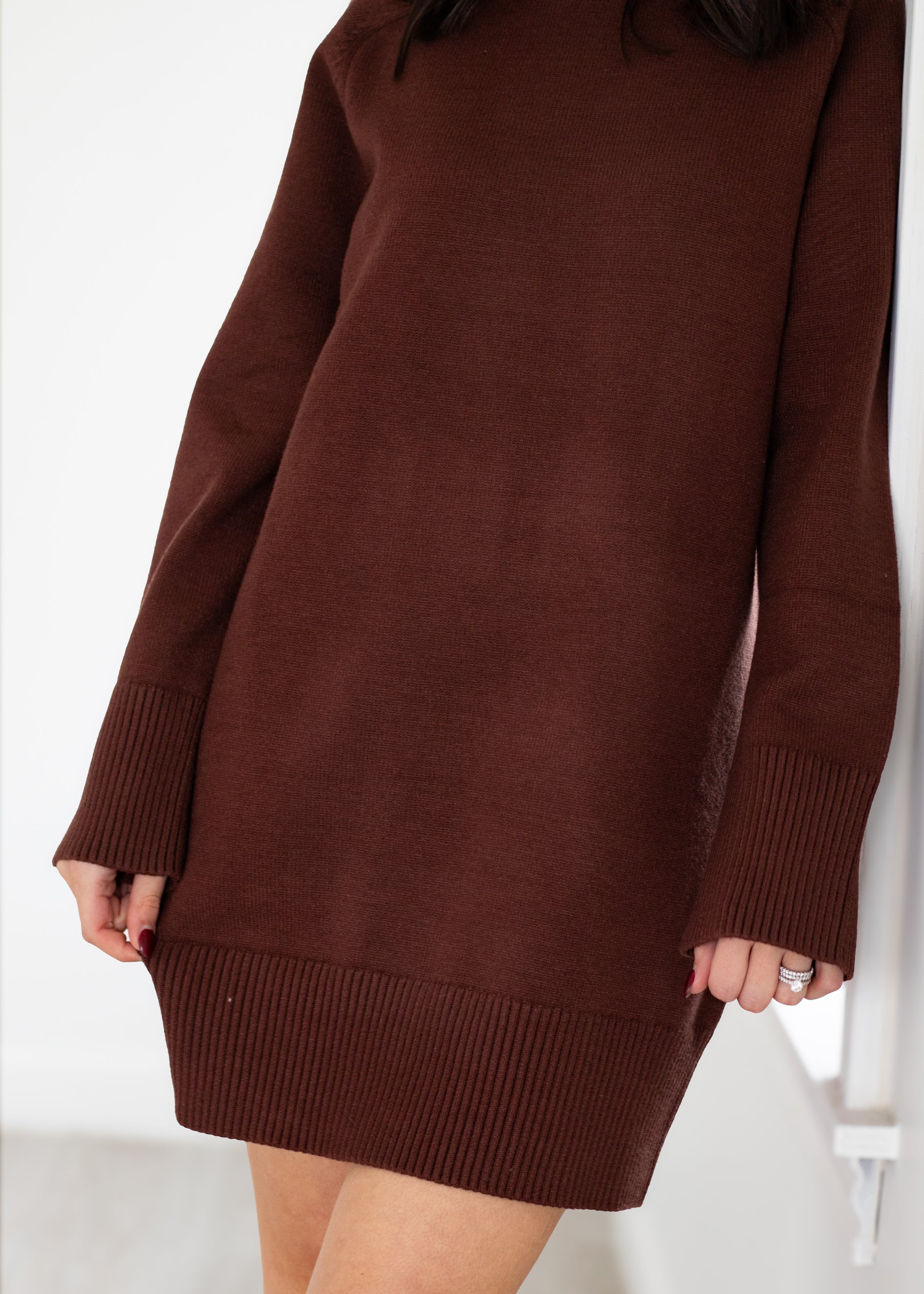 Brown sweater dress worn by a person on a white background