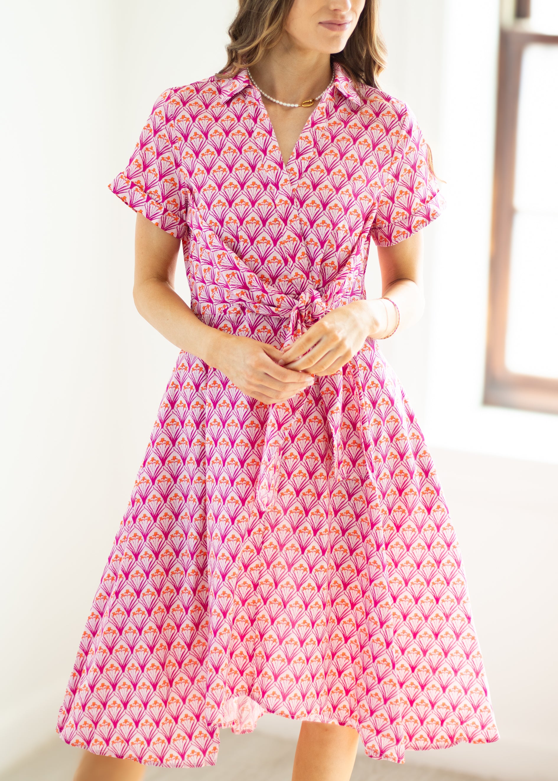 Woman wearing a pink patterned dress with a white background