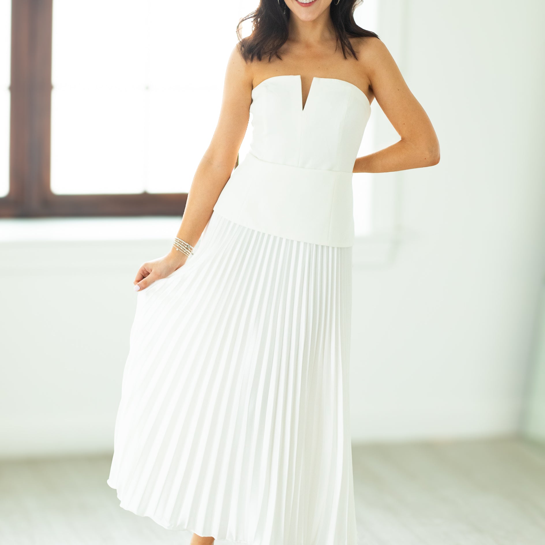 Woman wearing a white strapless dress in a bright room