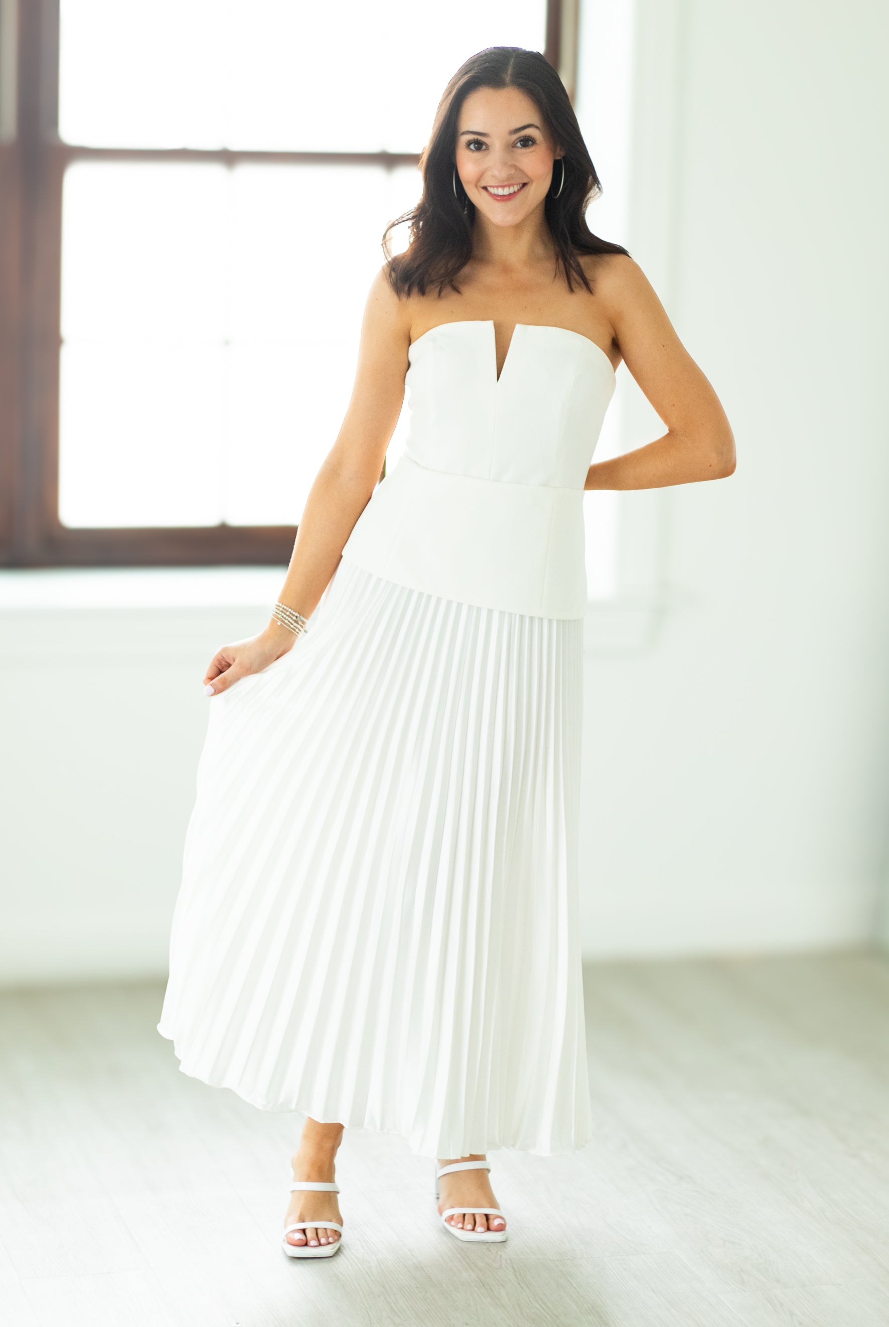 Woman wearing a white strapless dress in a bright room