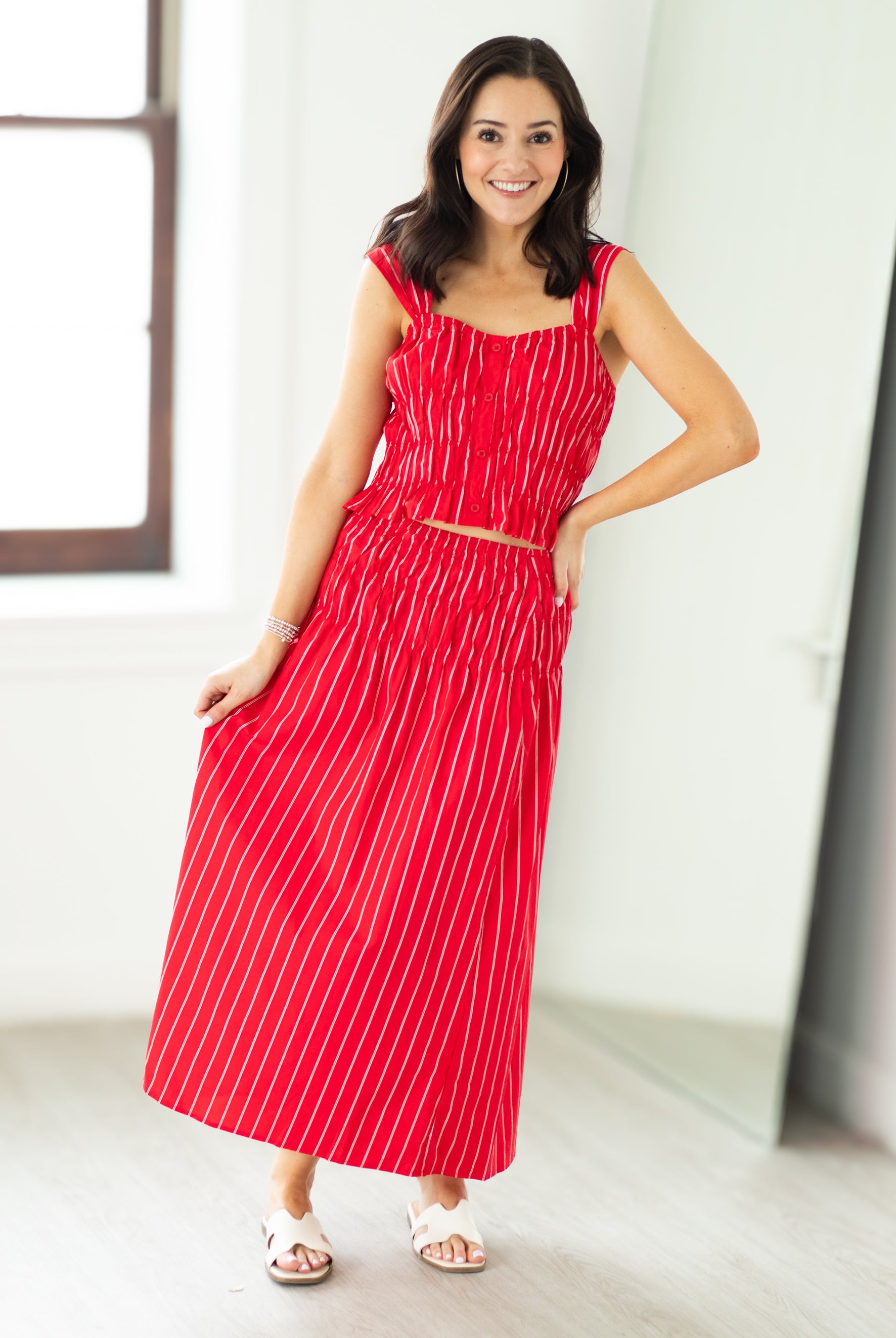 Woman wearing a red and white striped dress standing in a bright room.