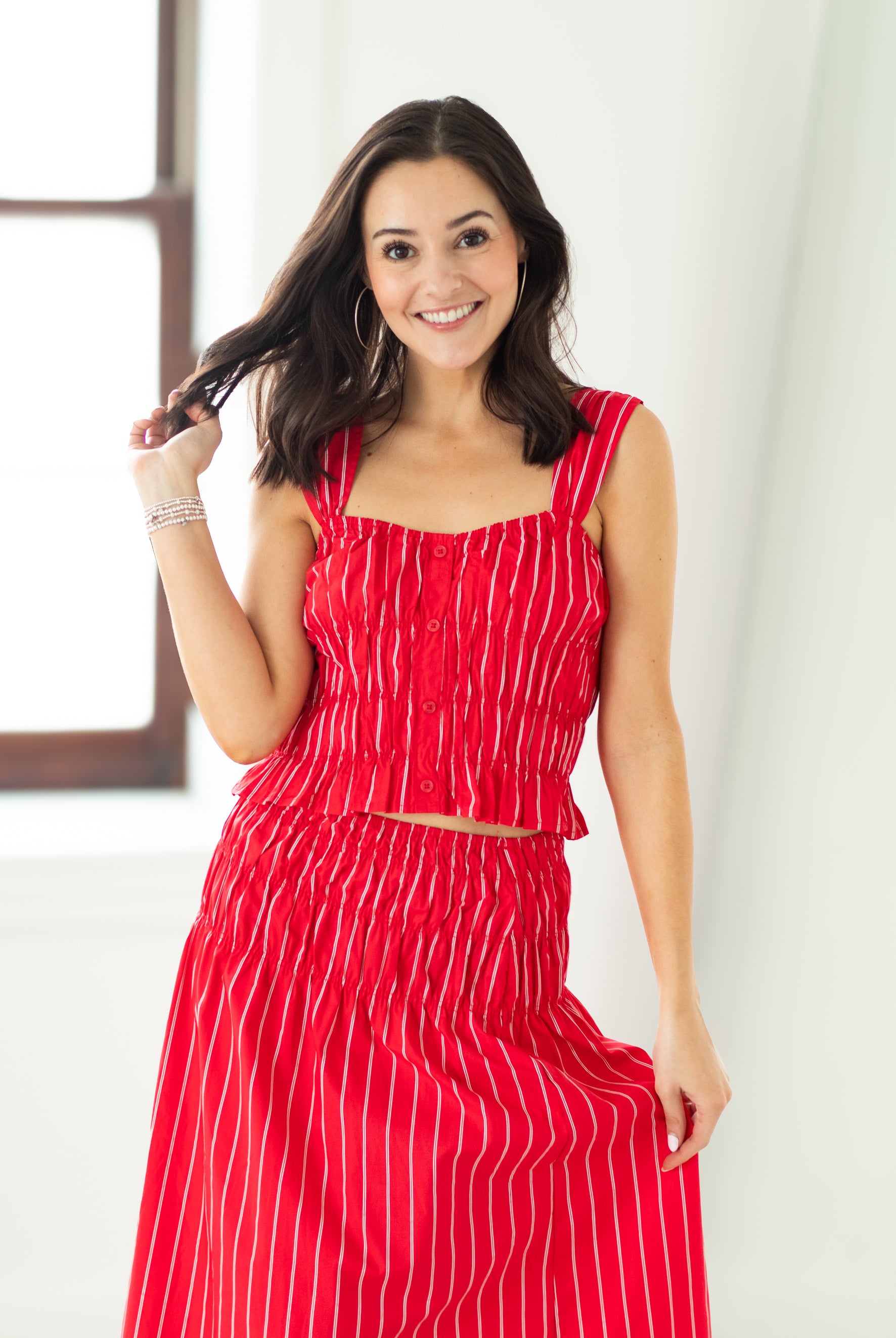 Woman wearing a red dress with white stripes against a white background