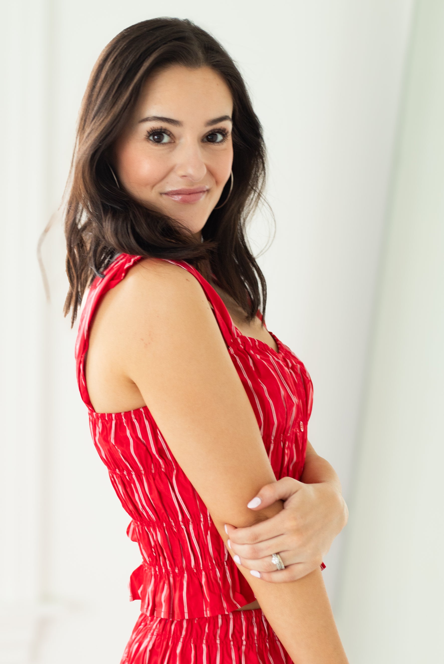 Woman wearing a red dress with white patterns against a white background