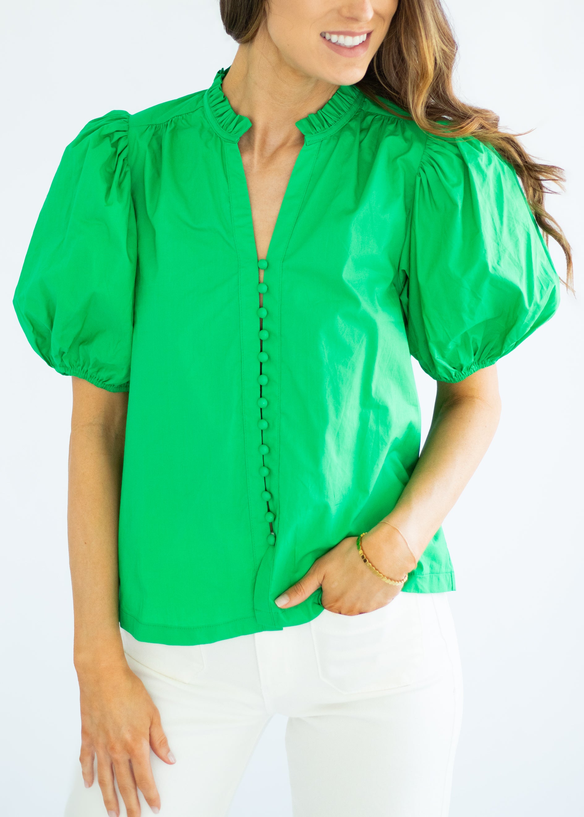 Woman wearing a green blouse with puff sleeves on a white background