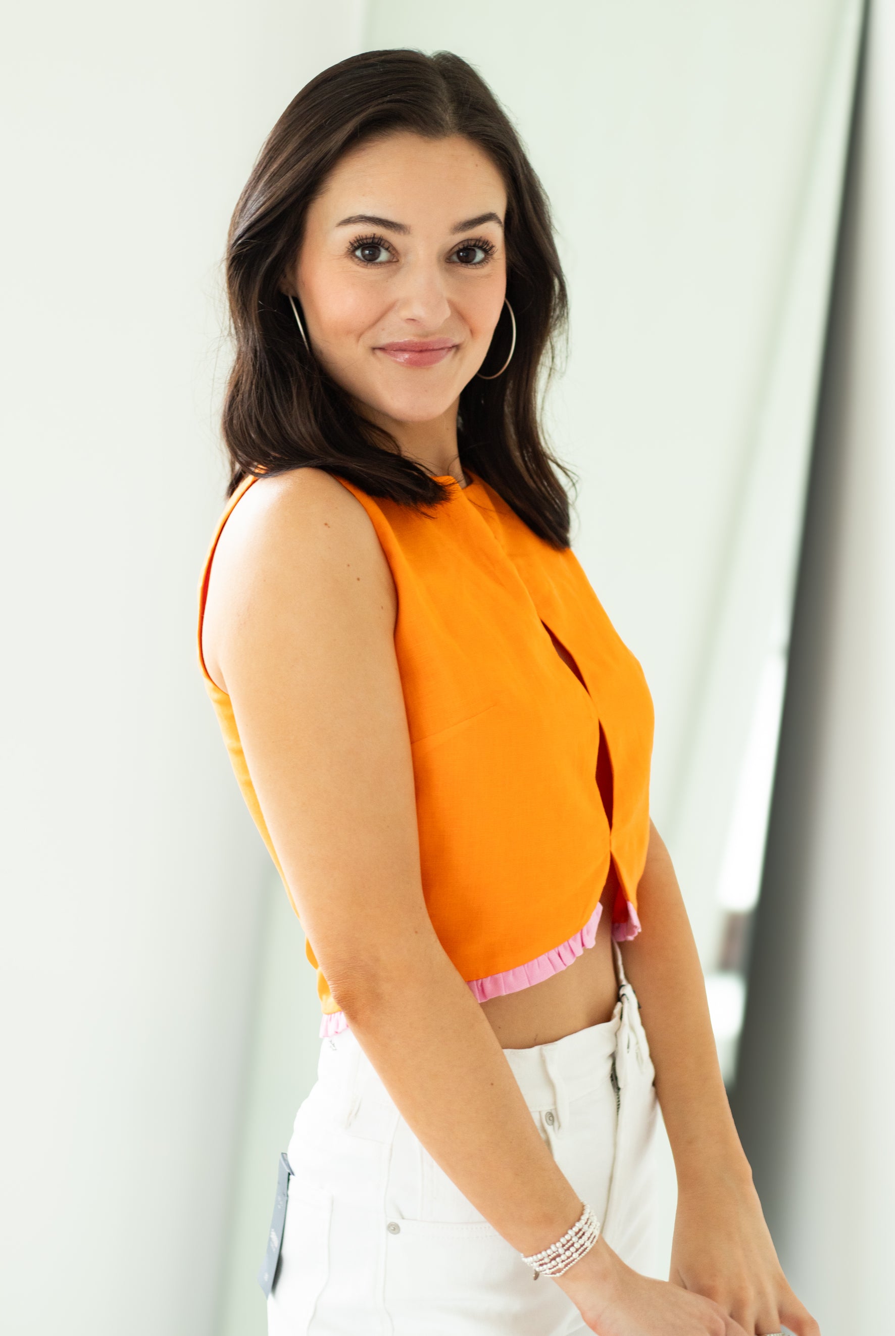 Woman wearing an orange top with a white background