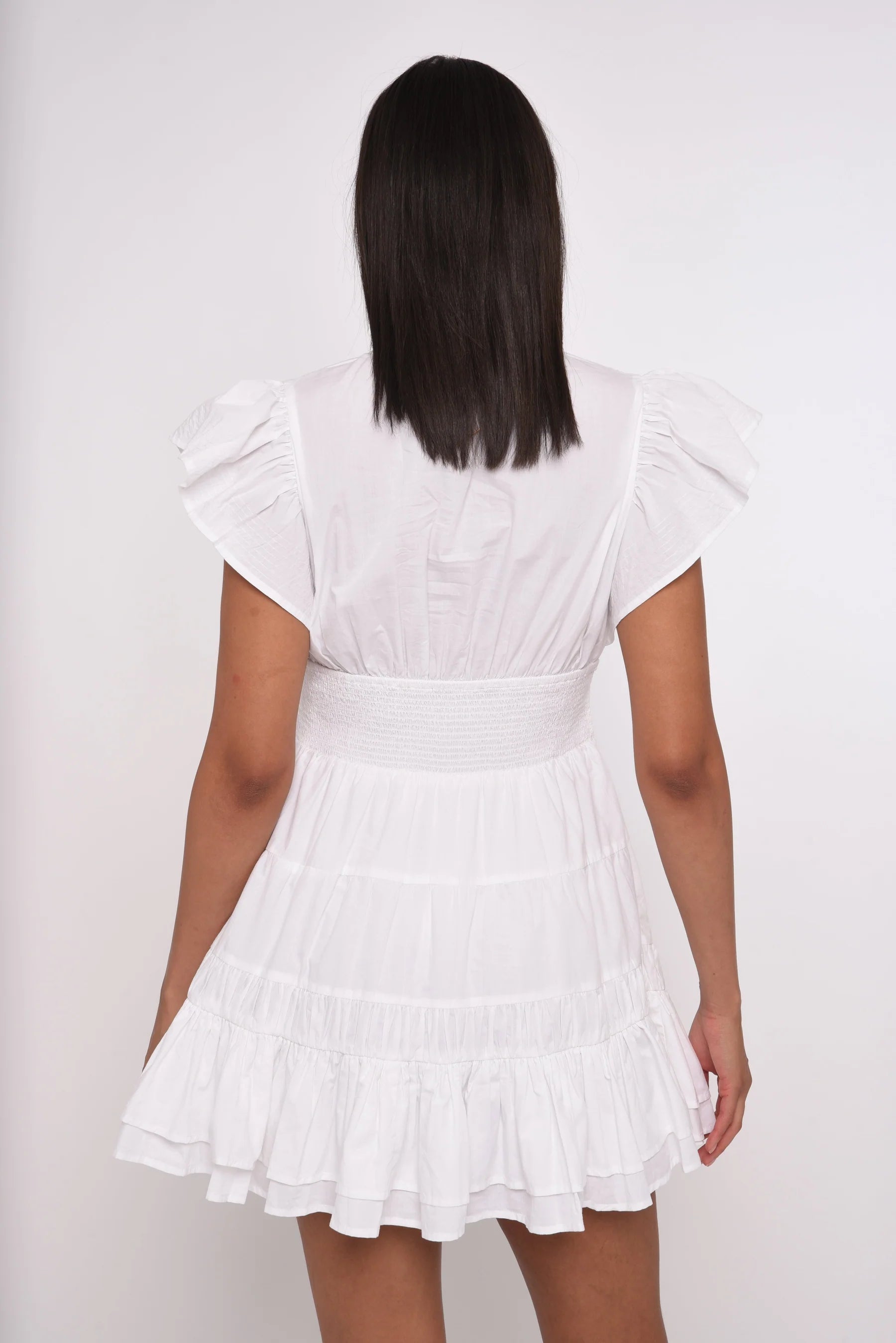 Woman wearing a white dress with a plain background