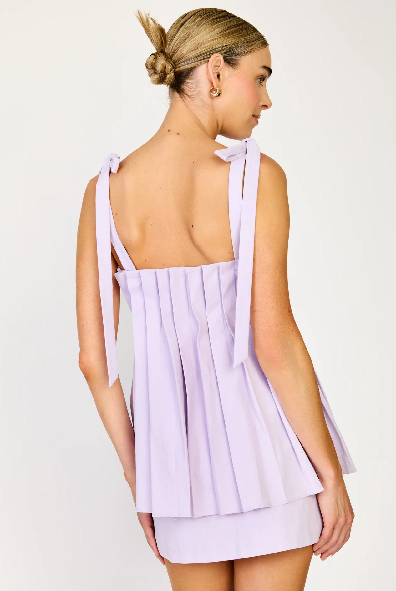 Woman wearing a light purple dress with a bow detail on a white background