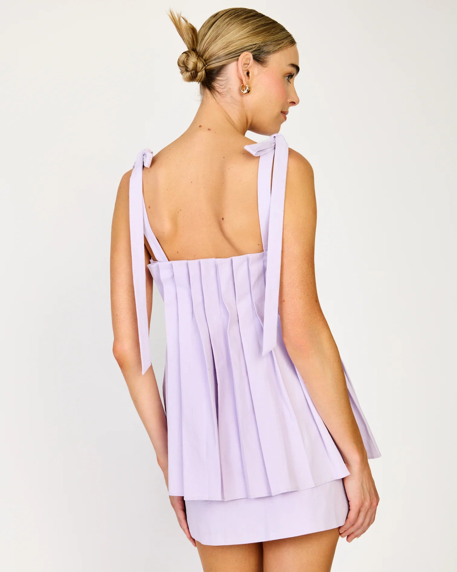 Woman wearing a light purple dress with a bow detail on a white background