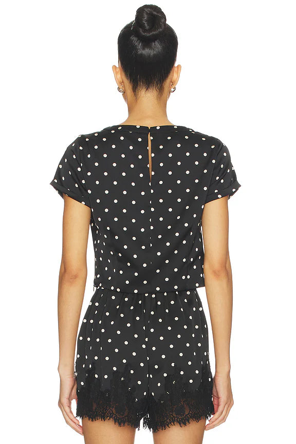 Black polka dot dress with lace hem on a white background