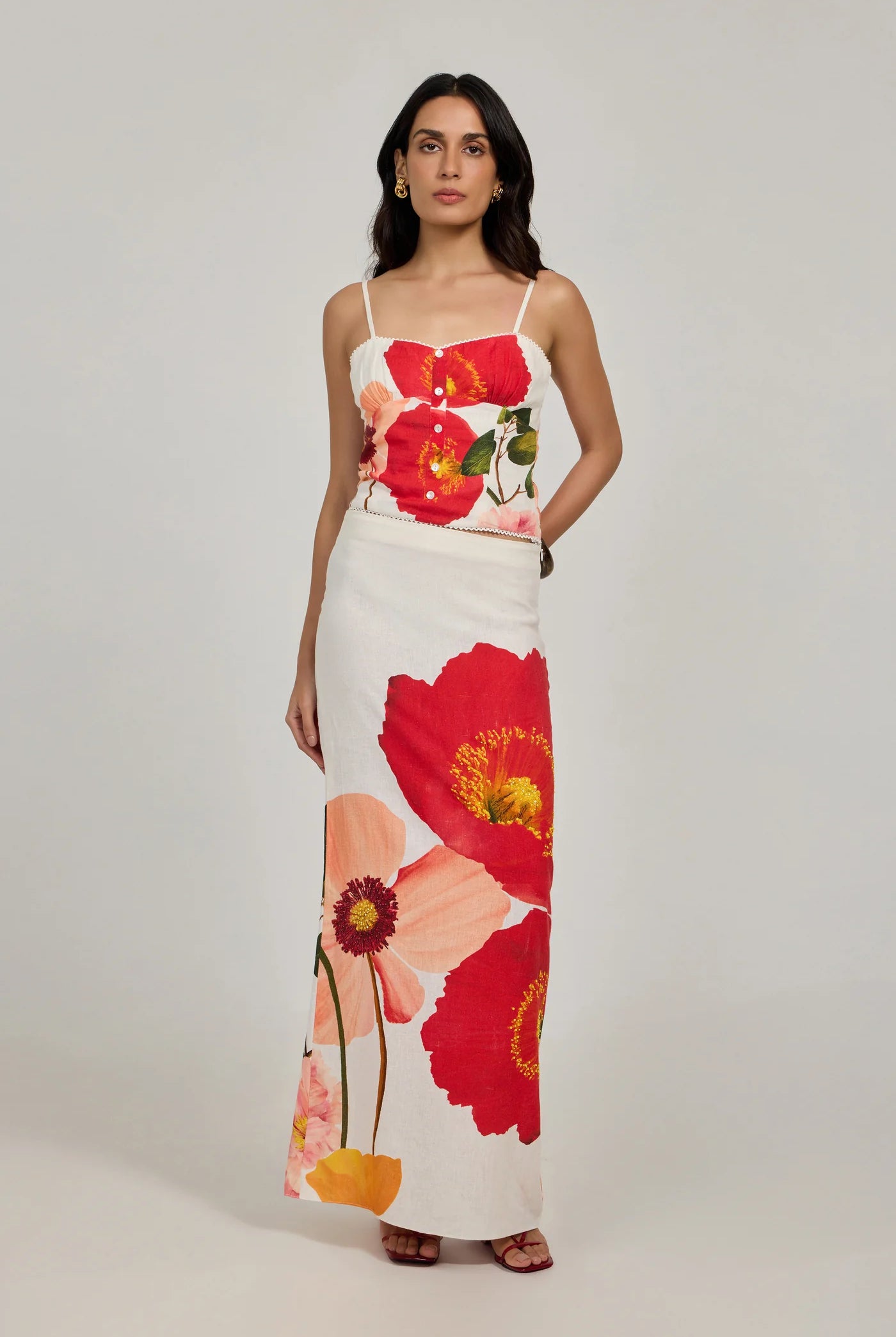 Woman wearing a floral dress with red and pink flowers on a plain background