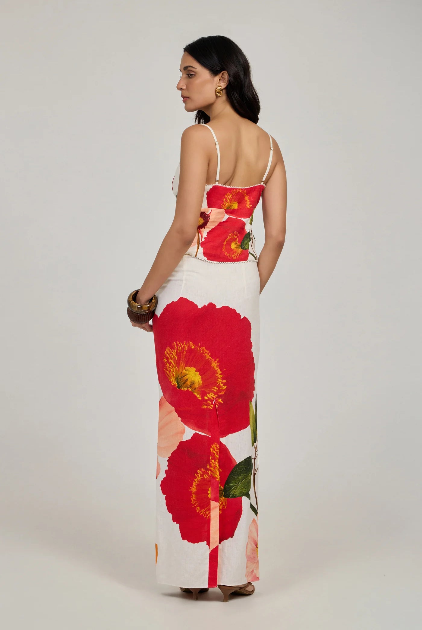 Woman wearing a floral dress with red flowers on a plain background