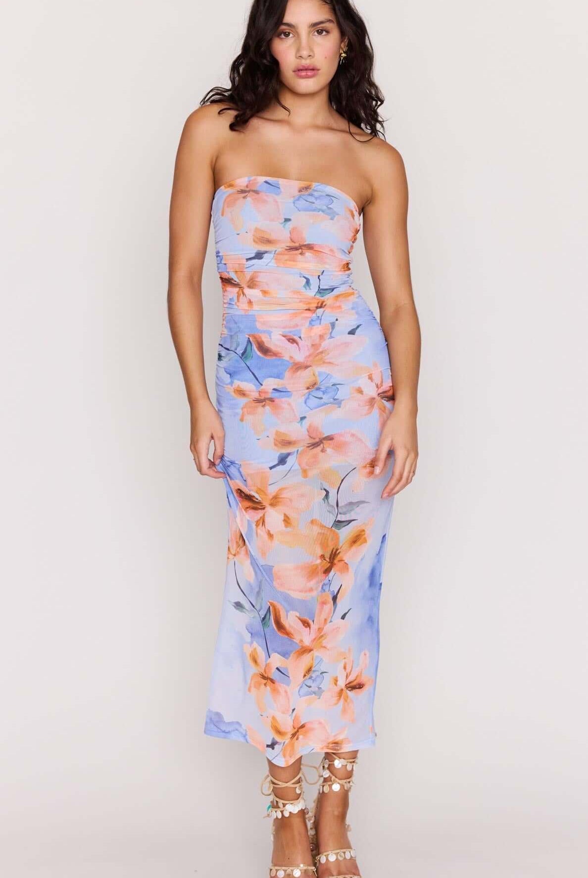 Woman wearing a strapless floral dress on a plain background