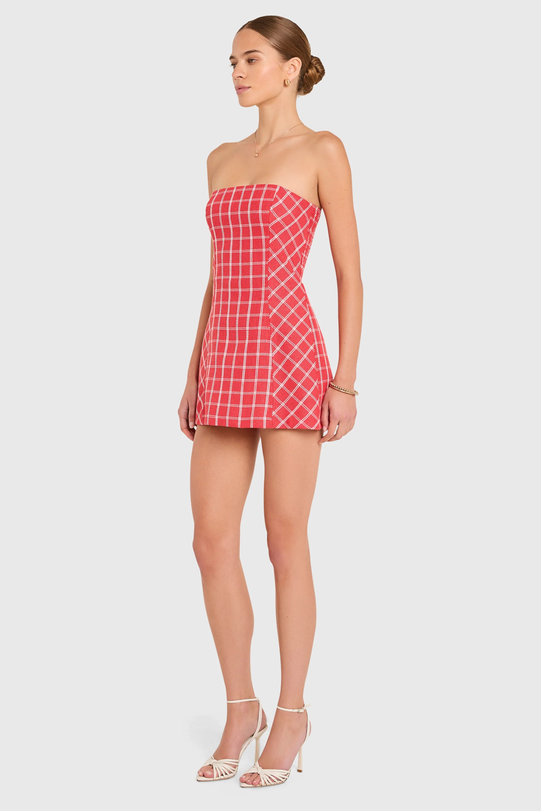 Woman wearing a red checkered strapless dress on a white background