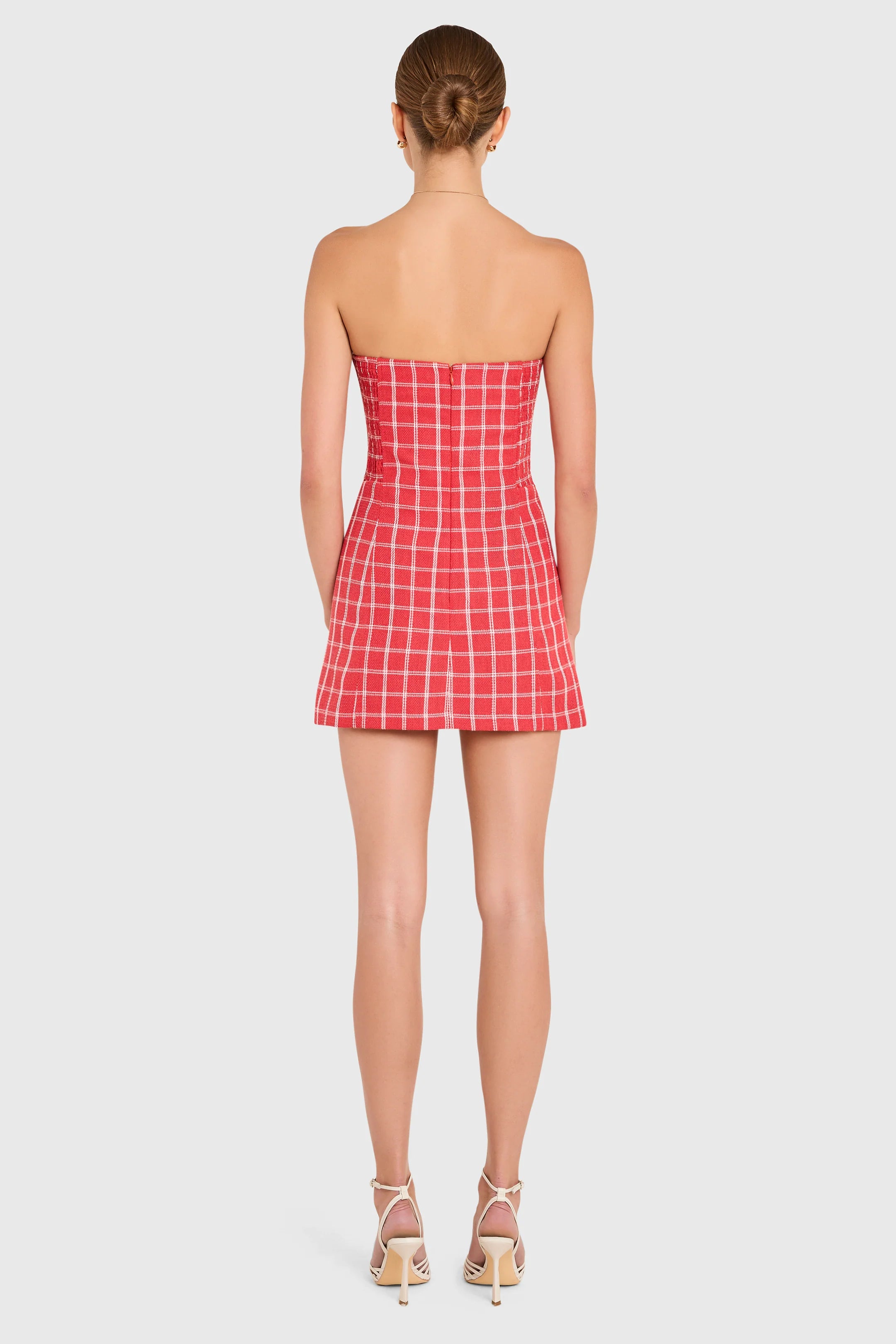 Person wearing a red checkered strapless dress on a white background