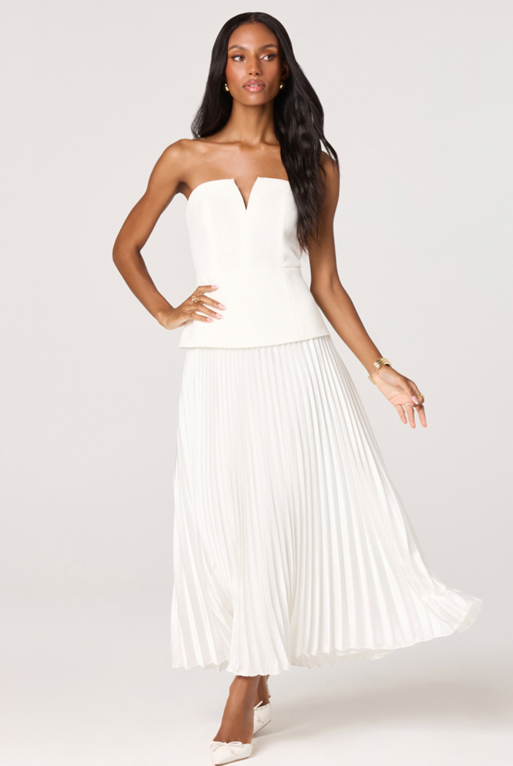 Woman wearing a white strapless dress with pleated skirt on a white background
