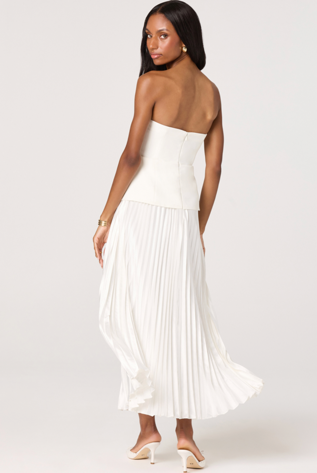 Woman wearing a white strapless pleated dress on a white background