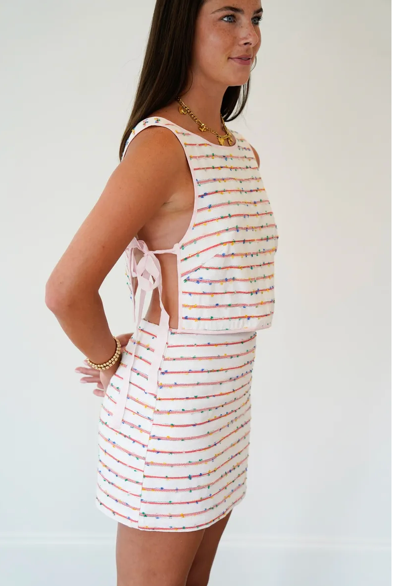 Woman wearing a striped dress with cut-out sides against a plain background