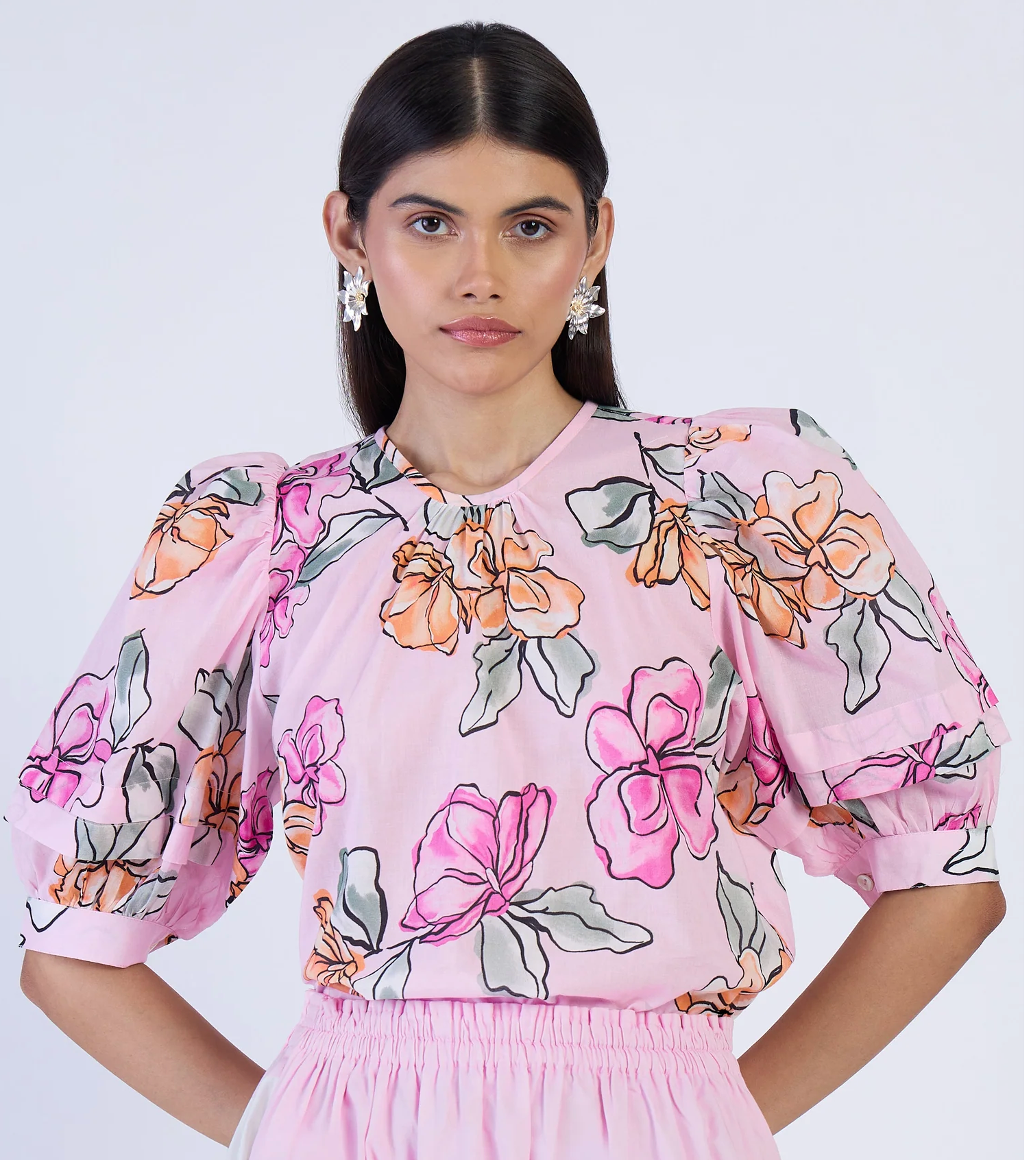 Woman wearing a pink floral blouse against a white background