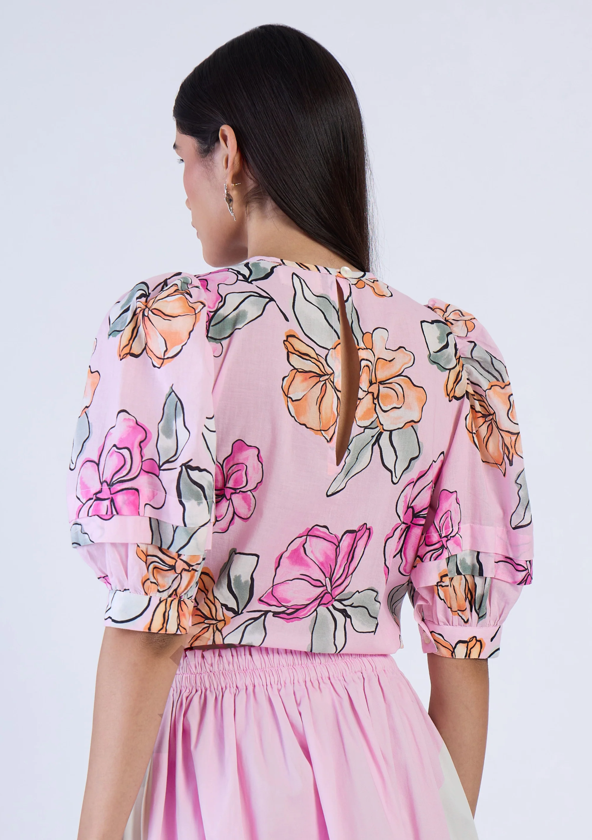 Woman wearing a pink floral dress against a white background