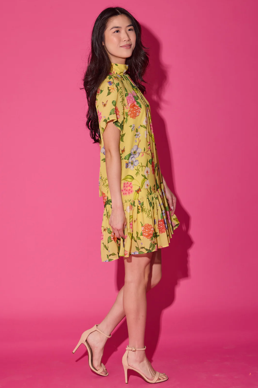 Woman wearing a yellow floral dress against a pink background