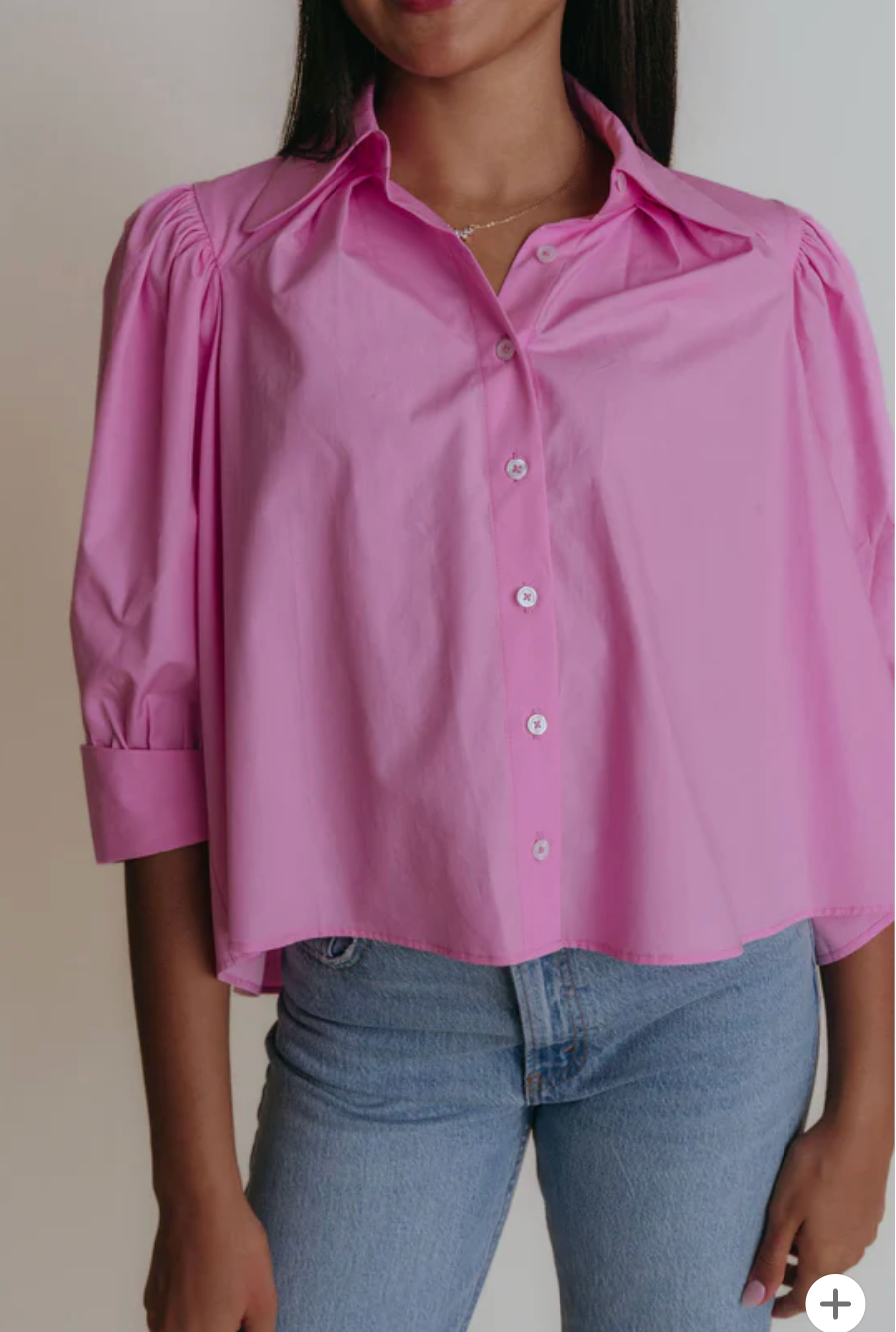 Person wearing a pink blouse and blue jeans against a neutral background