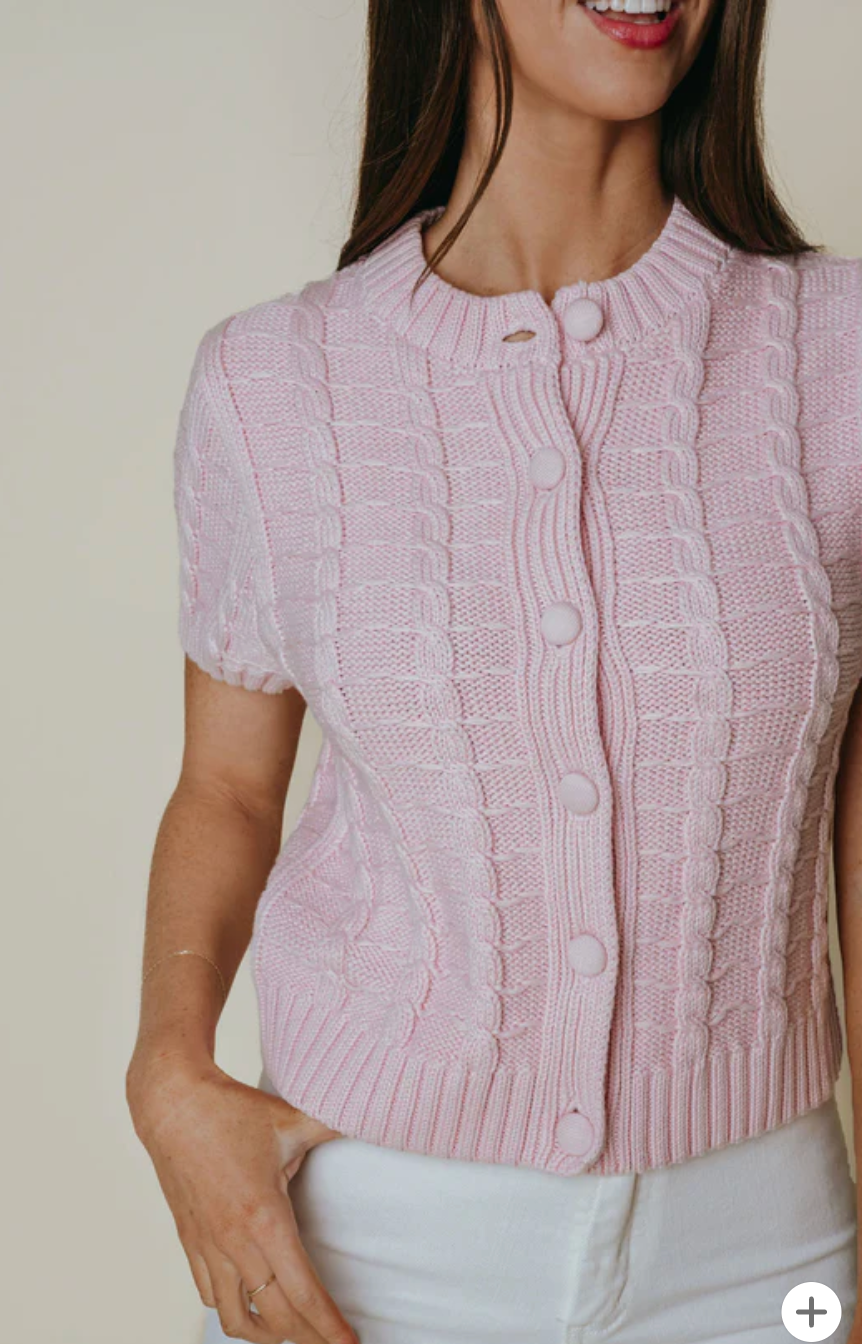 Woman wearing a pink knitted cardigan against a neutral background