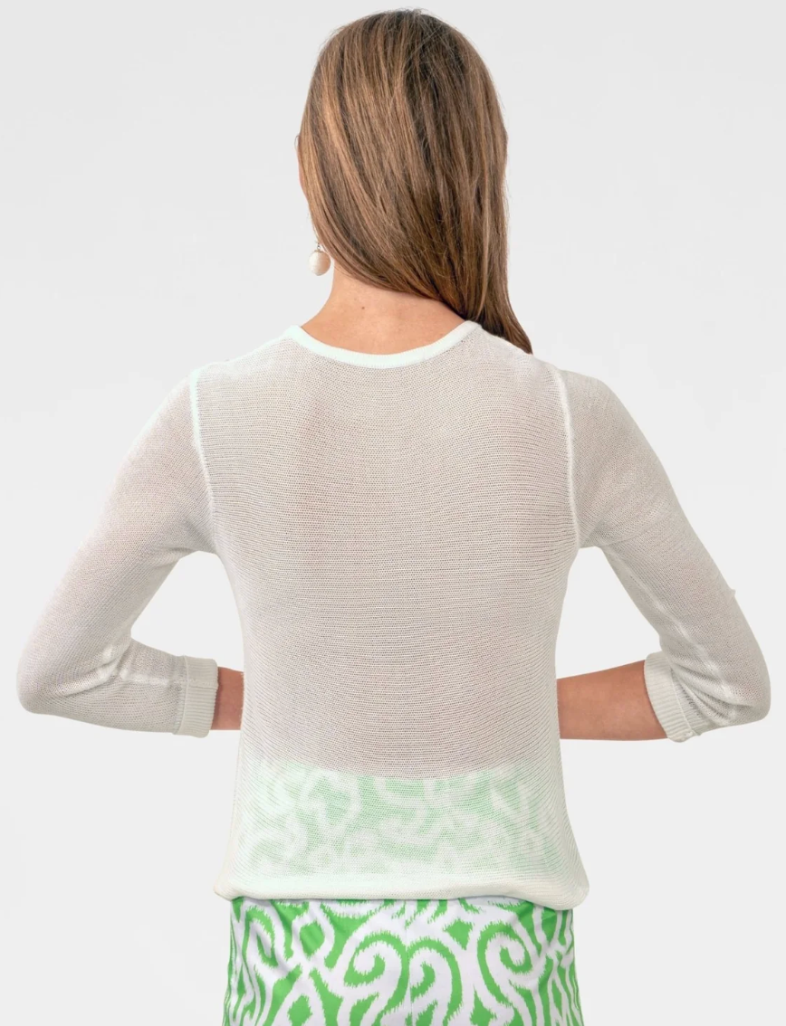 Woman wearing a light-colored sweater over a patterned skirt on a white background