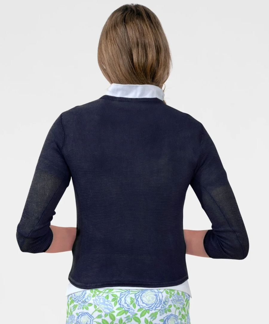 Person wearing a navy long-sleeve shirt over a white collared shirt with a floral skirt on a white background