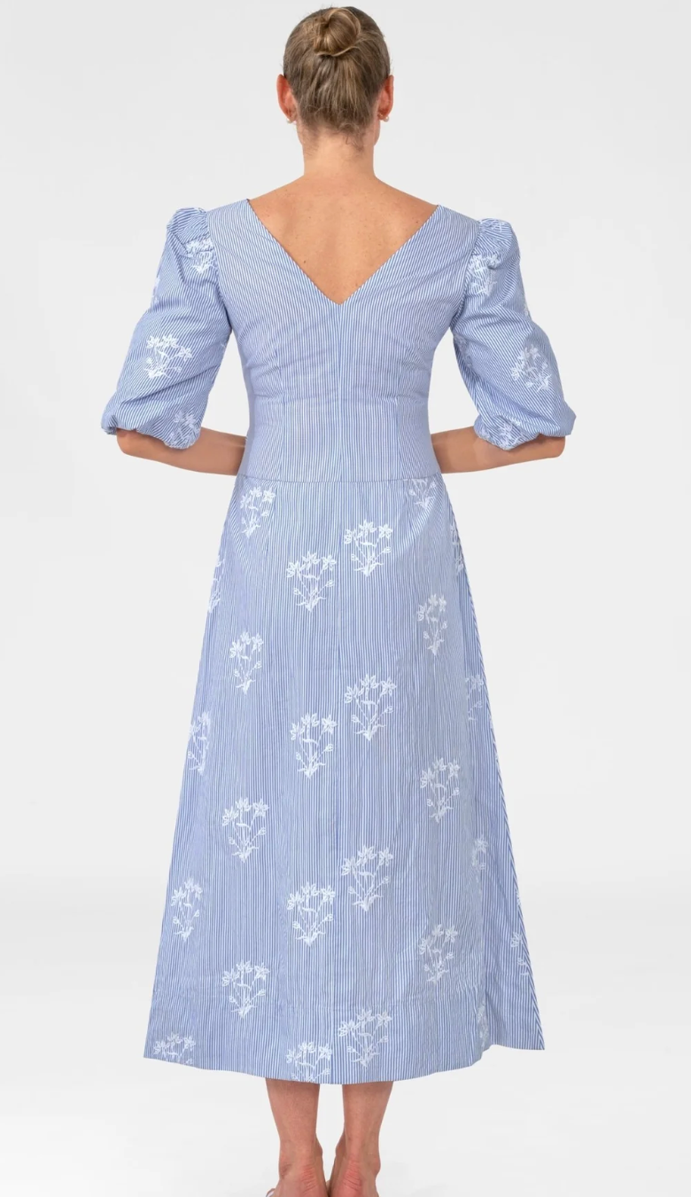 Woman wearing a blue dress with white floral patterns on a white background