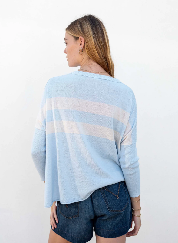 Woman wearing a light blue striped sweater and denim shorts against a white background