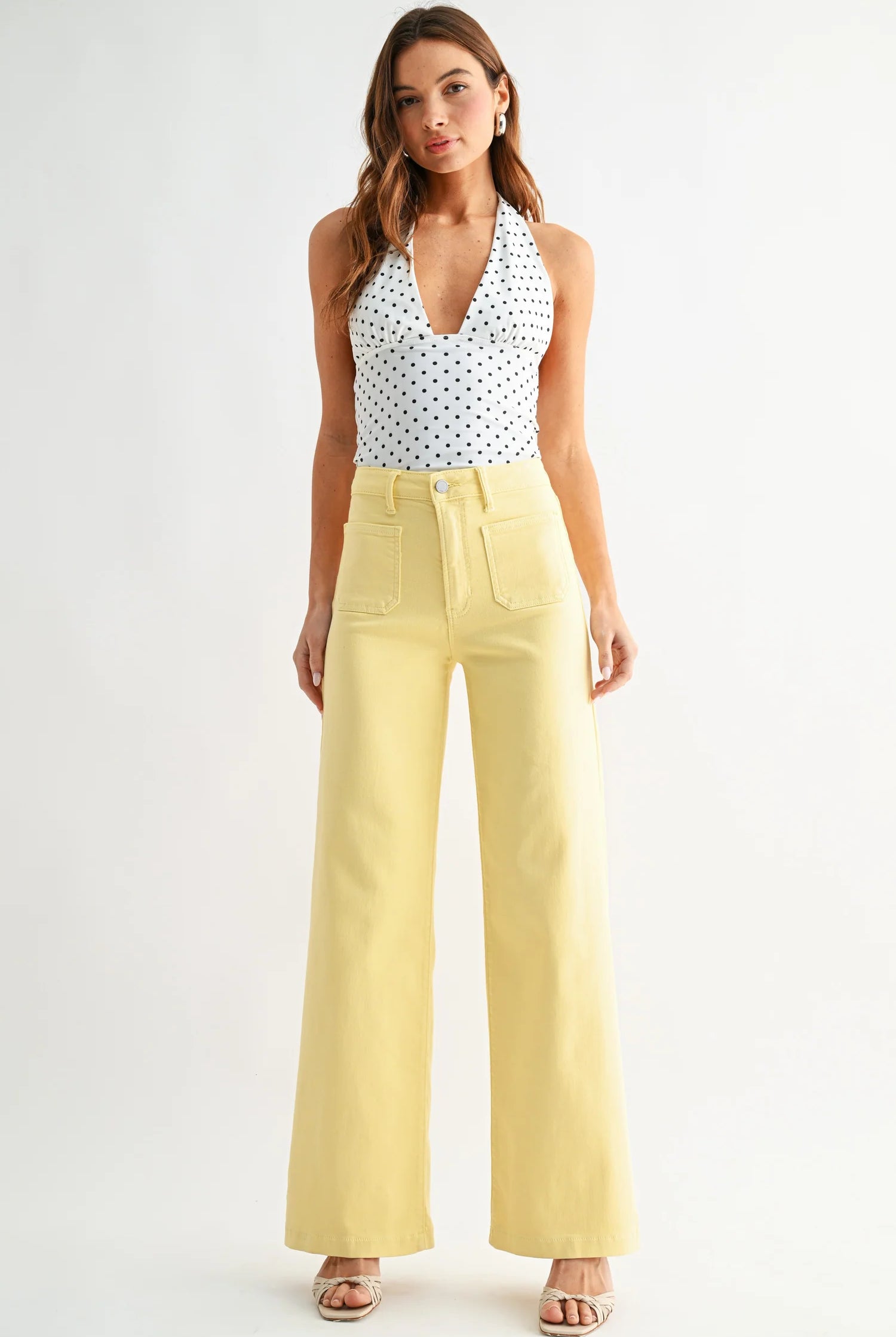 Woman wearing a polka dot top and yellow pants on a white background