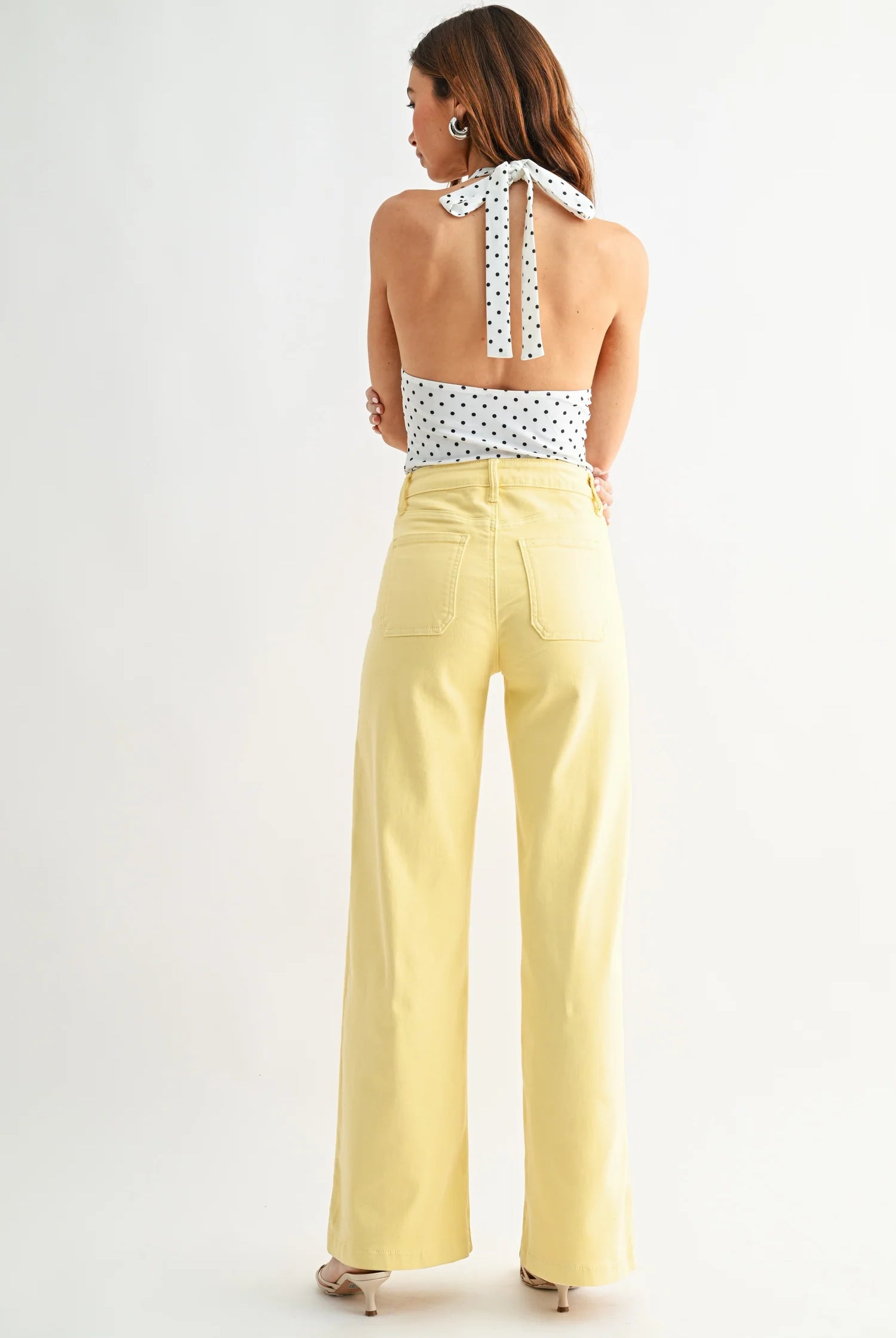 Woman wearing a polka dot top and yellow pants on a white background