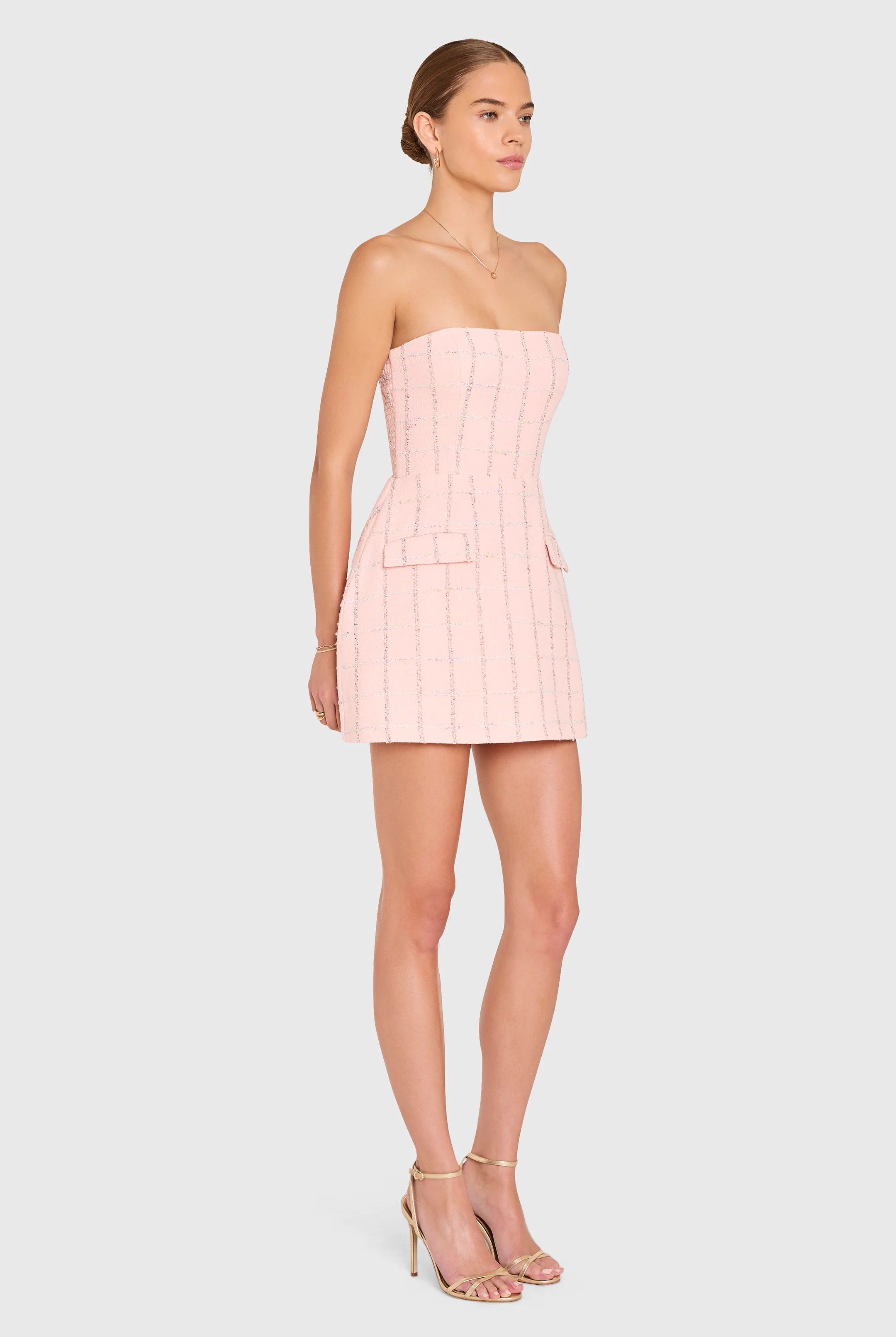 Woman wearing a light pink strapless dress on a white background