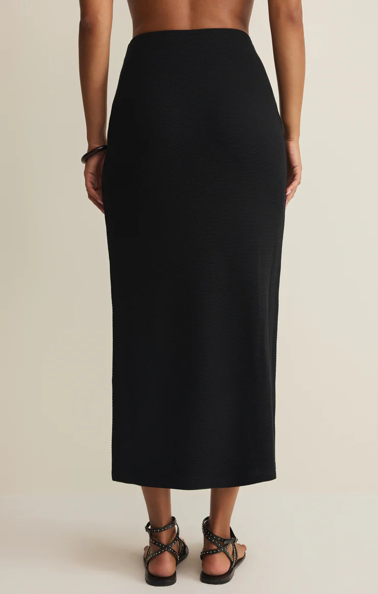 Person wearing a black skirt on a beige background