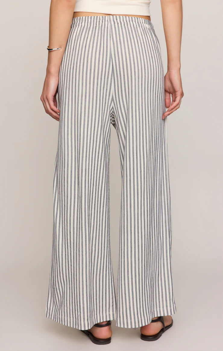 Person wearing black and white striped wide-leg pants on a plain background