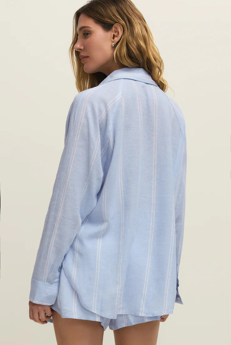 Woman wearing a light blue striped shirt and shorts on a plain background