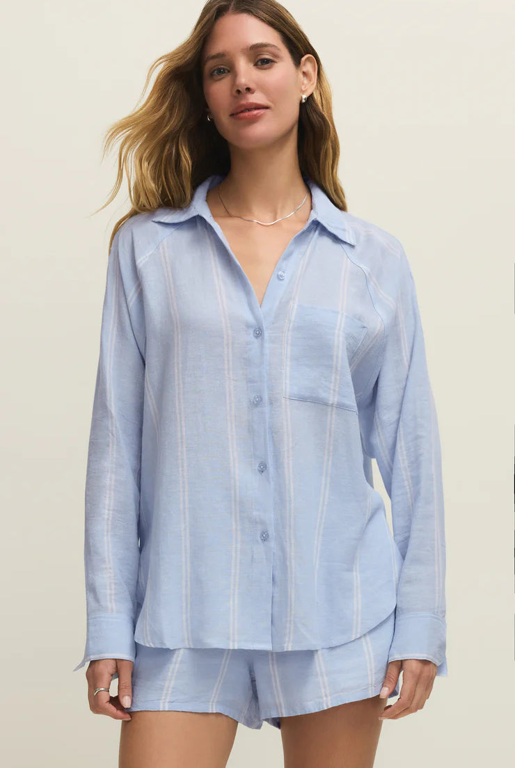 Woman wearing a light blue striped shirt and shorts set on a plain background