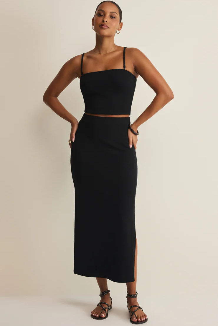 Woman wearing a black two-piece outfit on a beige background