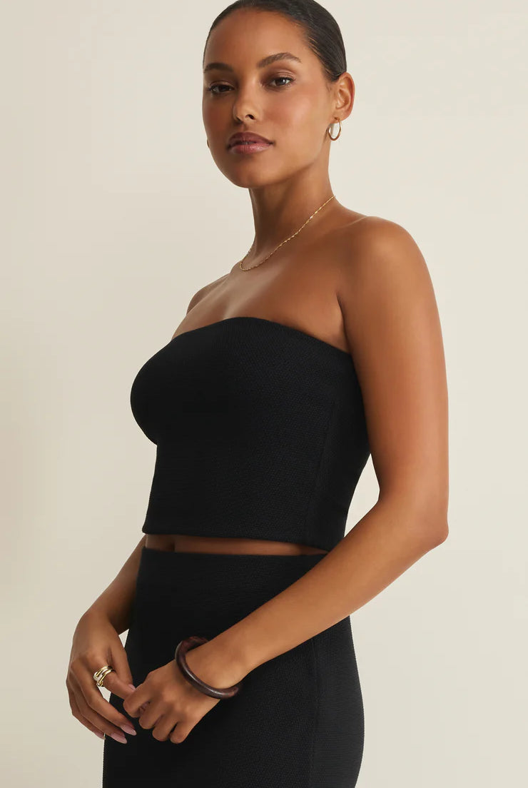 Woman wearing a black strapless top and skirt on a beige background