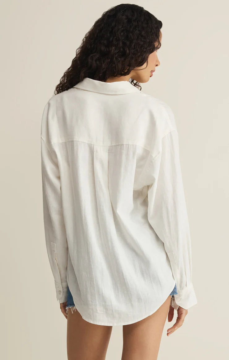 Woman wearing a white button-up shirt against a beige background