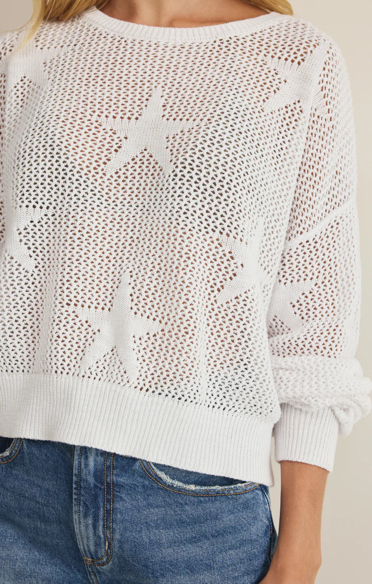 White mesh sweater with star patterns worn by a person, against a neutral background