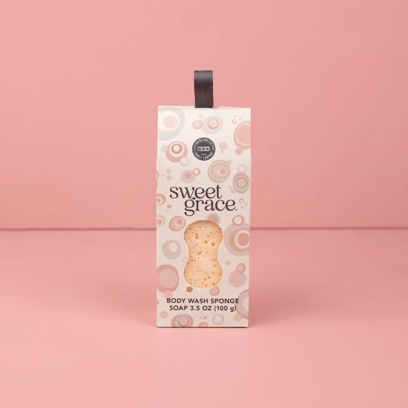 Box of 'sweet grace' body wash sponge on a pink background