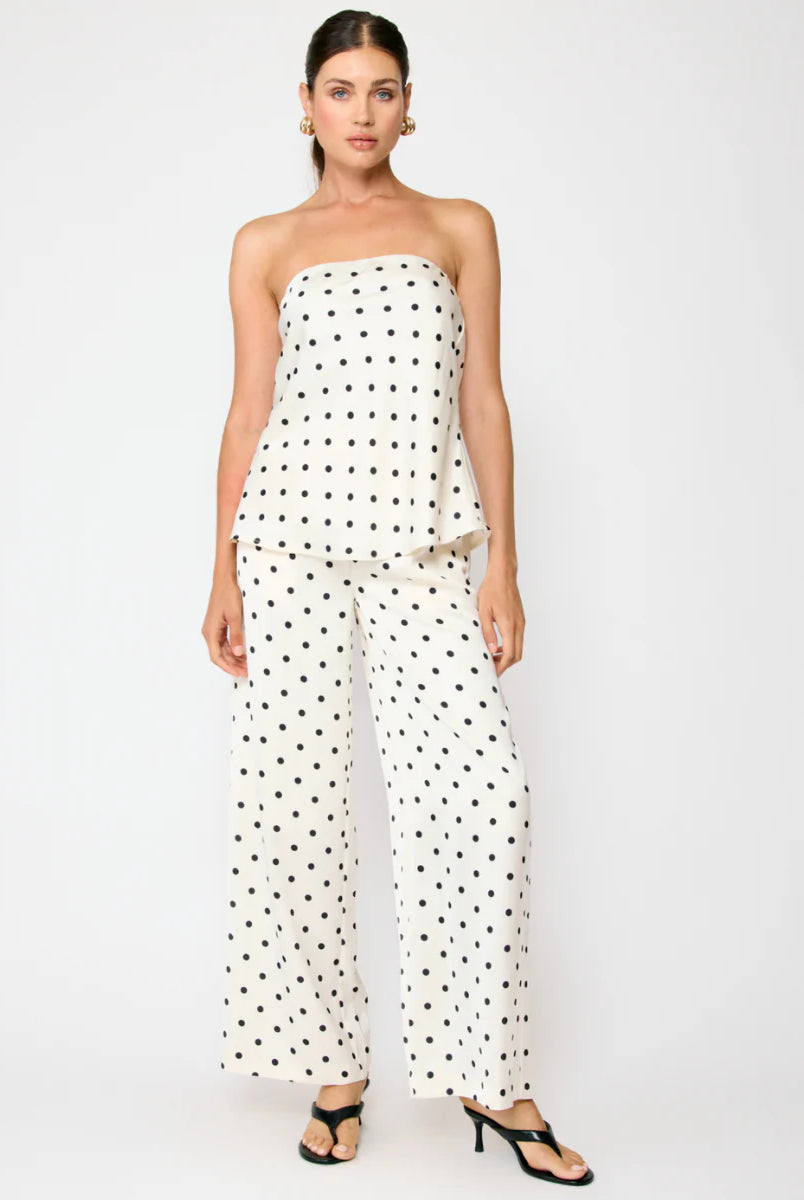 Woman wearing a strapless polka dot top and wide-leg pants on a white background