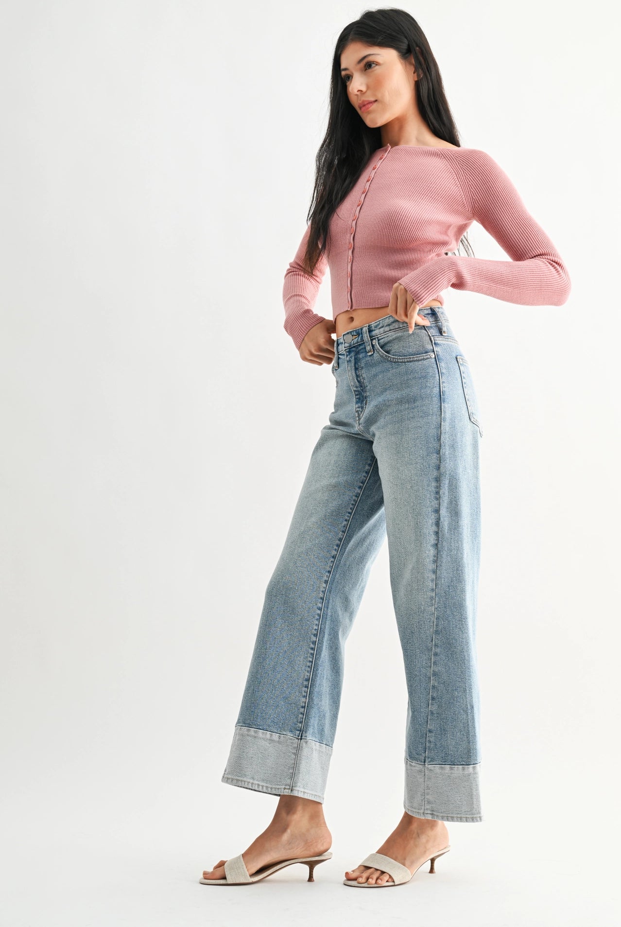 Woman wearing a pink top and blue jeans on a white background