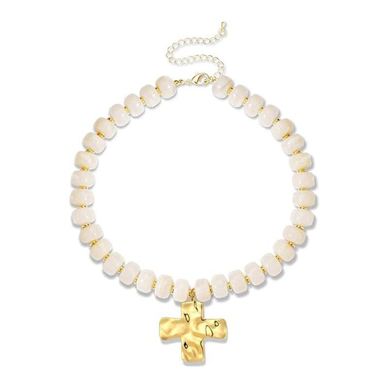 A beaded necklace featuring textured, rounded off-white beads separated by small gold spacers, with a polished gold cross pendant and an adjustable gold chain clasp, shown on a plain white background.