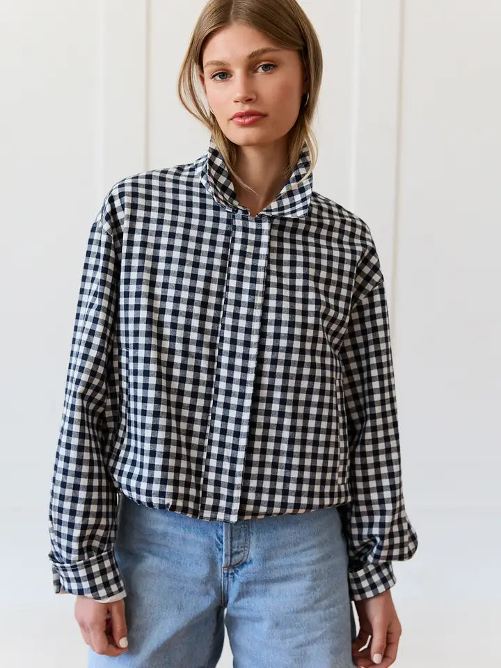Person wearing a black and white checkered shirt with blue jeans against a white background