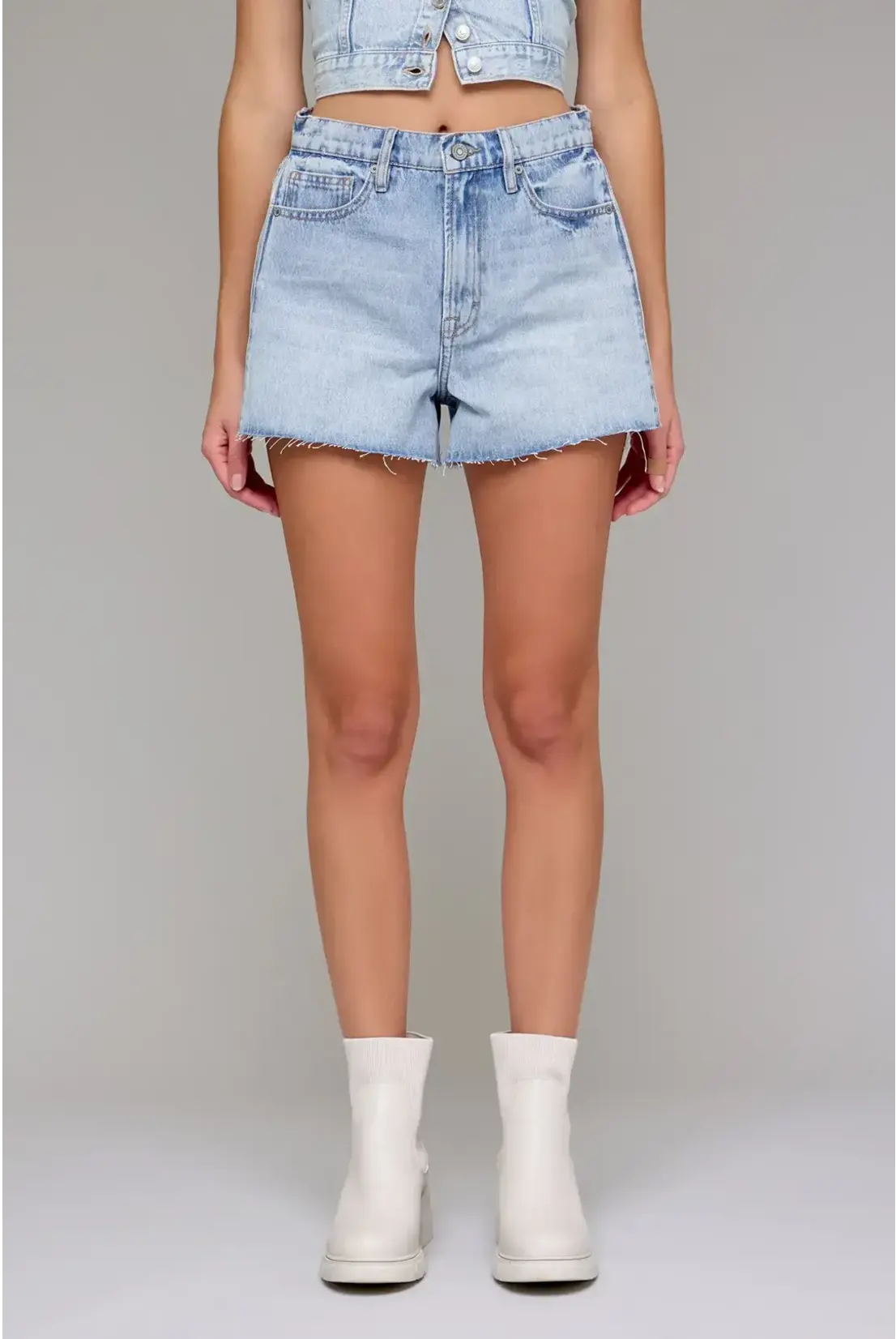 Person wearing light blue denim shorts on a gray background