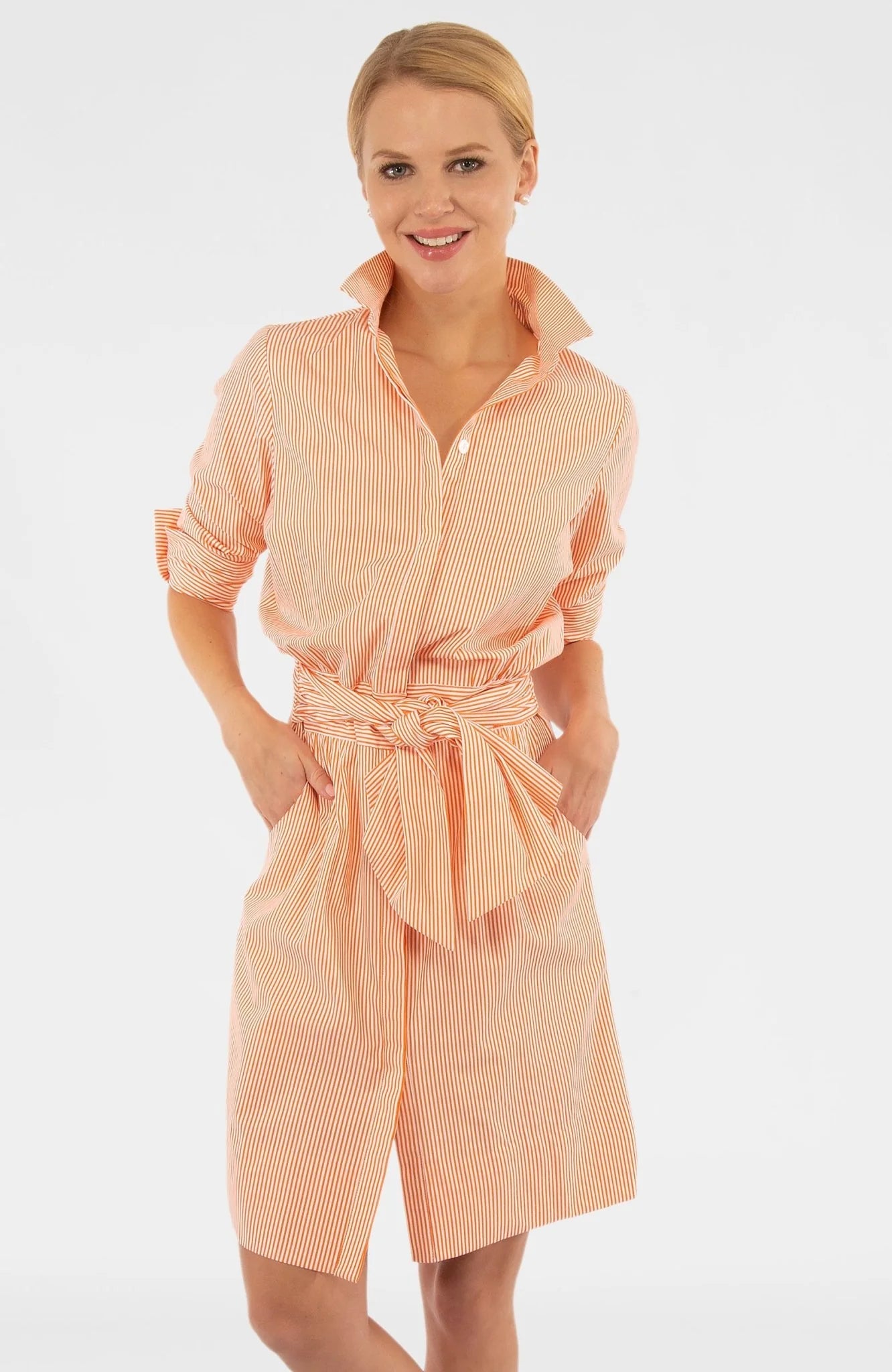 Woman wearing a peach-colored dress with a belt on a white background