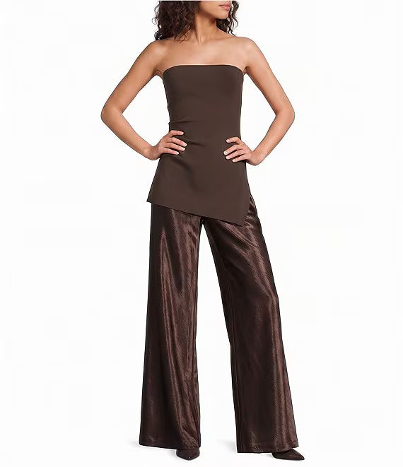 A woman modeling a dark brown strapless tube top paired with wide-leg metallic brown pants, posed against a plain white studio background.